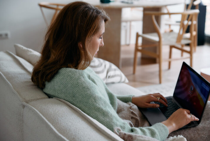 Woman working on her laptop while sitting on the couch