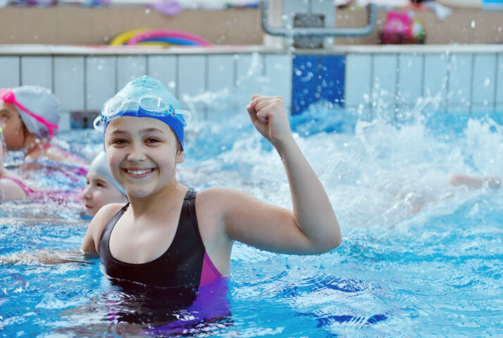 Happy children kids group at swimming pool class learning to swim